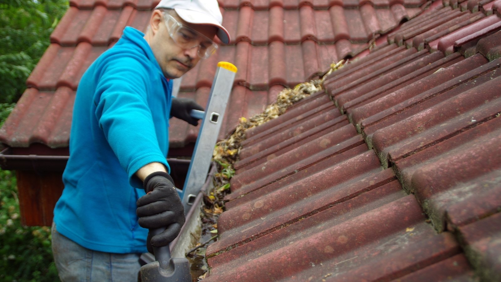 Technician maintaining a home gutter system