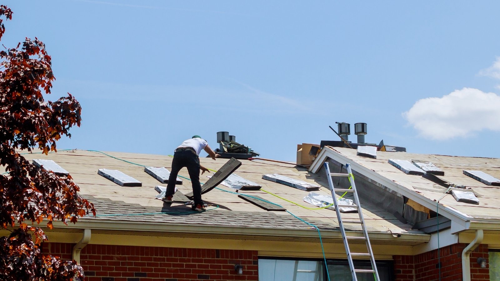 Roofer repairing shingles and addressing roof damage